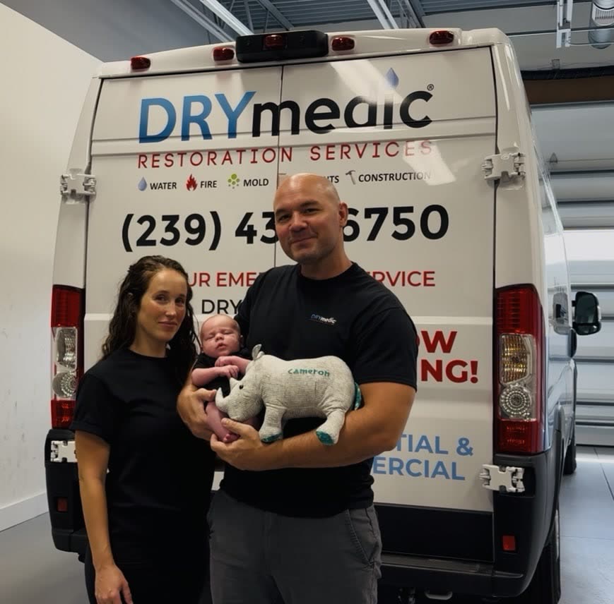 Nate and Kate, owners of DRYmedic Restoration of Cape Coral, with their newborn in front of their DRYmedic van