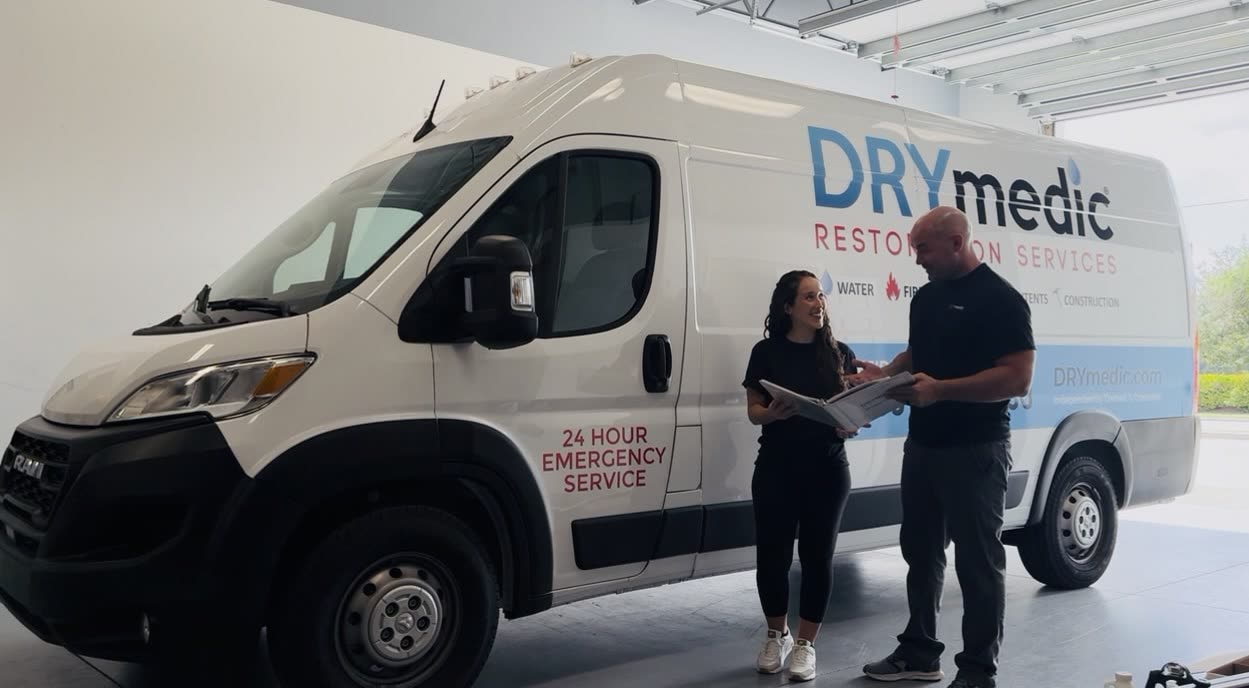 Nate and Kate reviewing a job binder beside the DRYmedic Cape Coral van